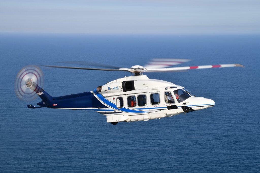 AW189 helicopter soaring over a blue ocean on offshore mission